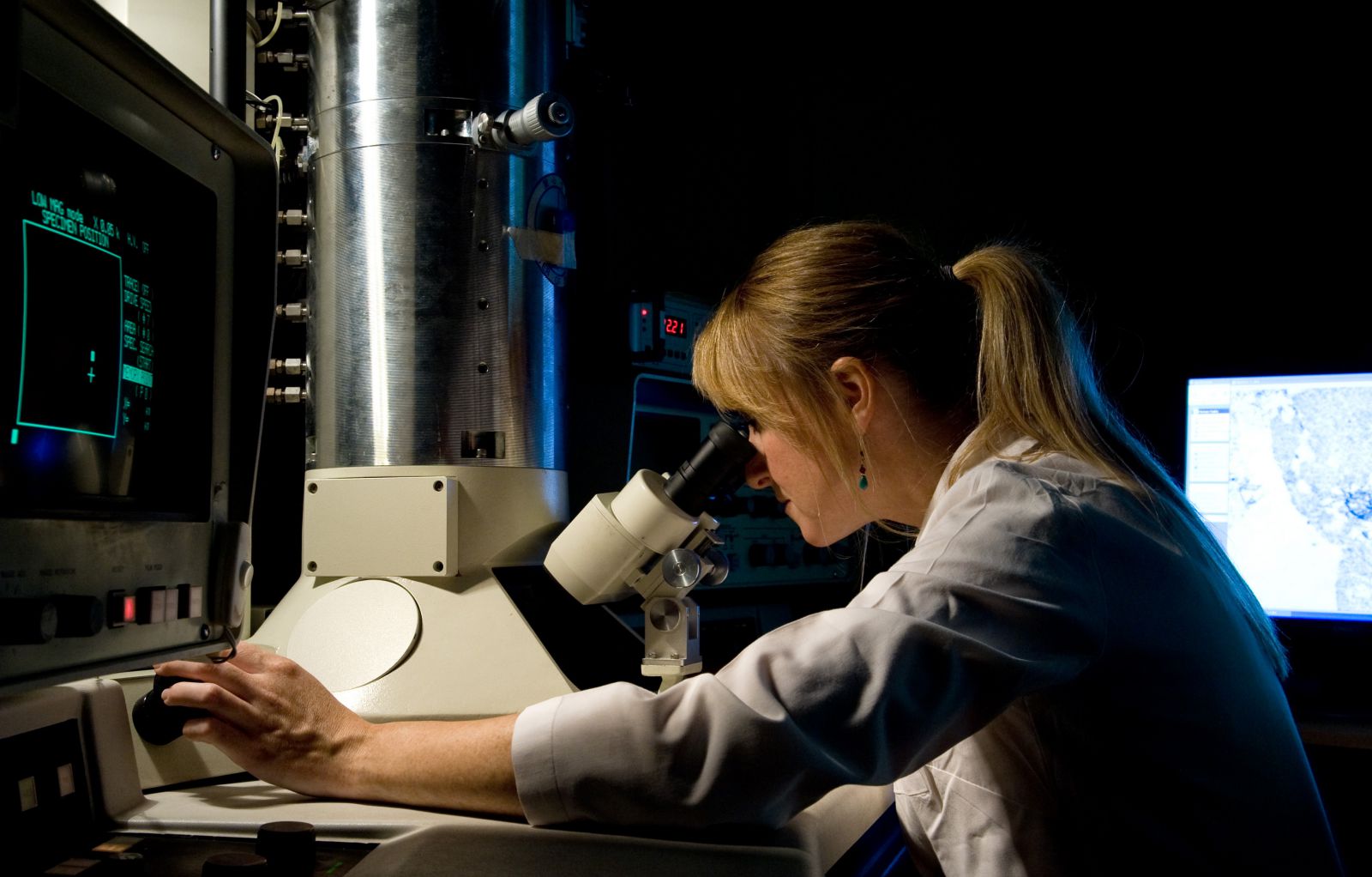 PhD student looks through a microscope in a science lab at the University of Sussex