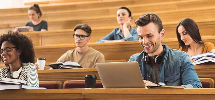 man in lecture hall with other students sitting behind him